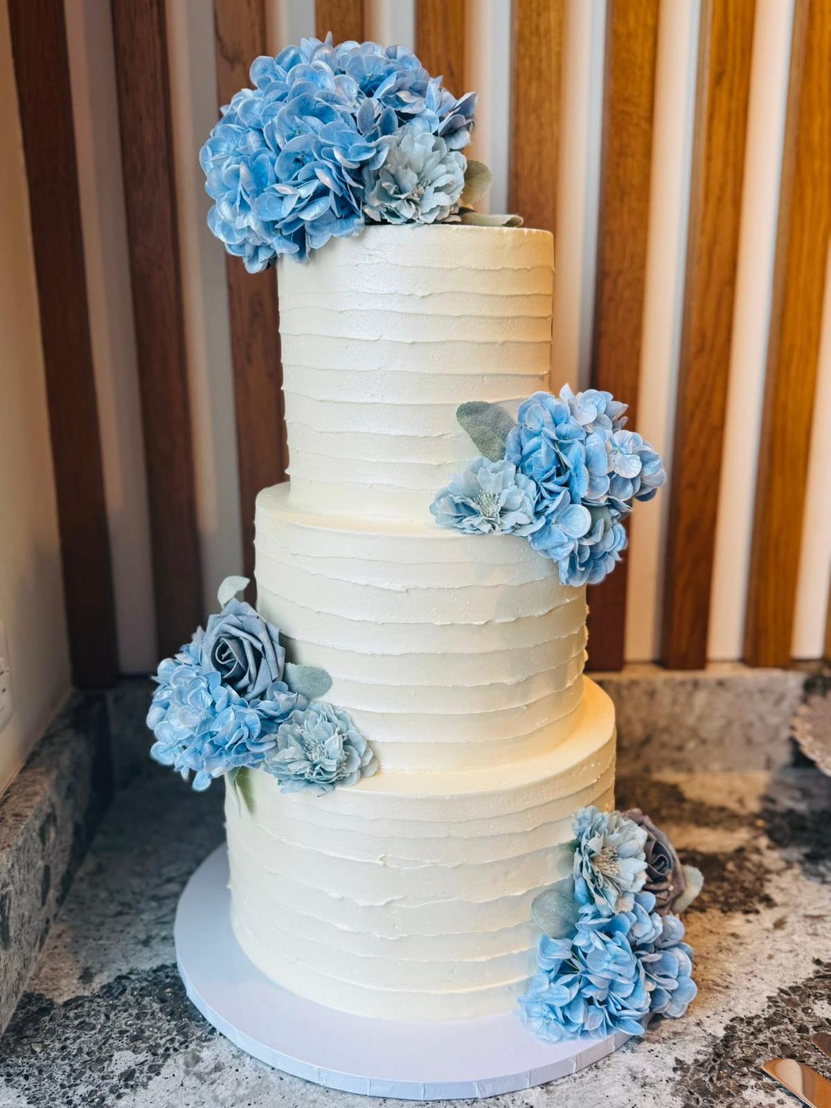 Tiered white cake decorated with soft blue flowers